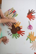 Students and teacher making Thanksgiving turkey crafts in classroom