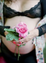 Pregnant woman in lingerie holding flower