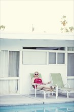 Woman laying on lawn chair near swimming pool