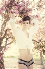 Woman in lingerie under flowering trees