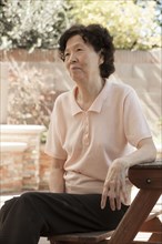 Older Asian woman sitting at picnic table