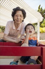Asian woman and grandson relaxing in backyard