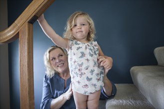 Grandmother helping granddaughter on staircase