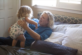 Grandmother and granddaughter playing on bed