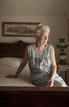 Pensive older woman sitting on bed