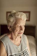 Pensive older woman sitting on bed