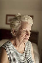 Pensive older woman sitting on bed