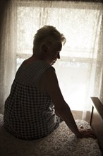 Pensive older woman sitting on bed