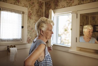 Older Caucasian woman examining herself in mirror