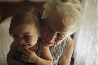 Grandmother and granddaughter hugging on bed