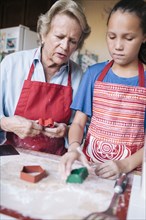 Grandmother and granddaughter cutting cookies from dough