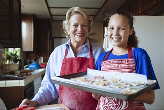 Grandmother and granddaughter baking cookies in kitchen