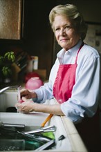 Older woman washing dishes in kitchen sink