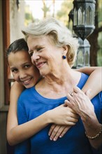Grandmother and granddaughter hugging on porch