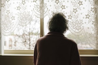 Pensive mixed race older woman looking out window