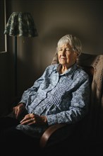 Older mixed race woman sitting in armchair