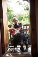 Caucasian woman playing electric guitar on porch