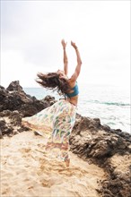 Woman dancing on rocky beach