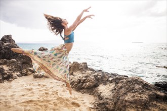 Woman dancing on rocky beach