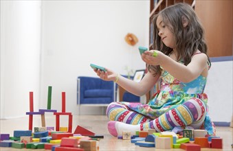 Caucasian girl playing with blocks on living room floor