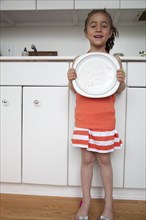 Caucasian girl holding empty plate in kitchen