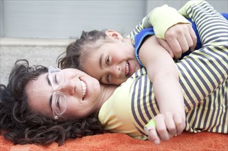Caucasian mother and daughter hugging on carpet