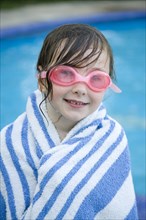 Caucasian girl wrapped in towel by swimming pool