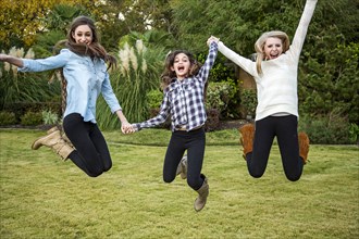 Caucasian teenage girls jumping for joy in backyard