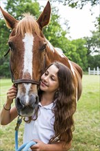 Teenage girl leading horse in field