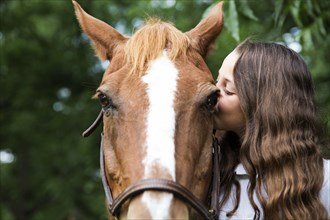 Teenage girl kissing face of horse
