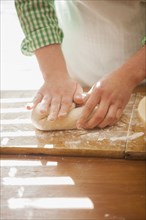 Close up of baker shaping dough on counter