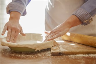 Baker pressing pie dough in dish