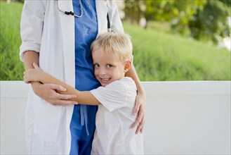 Close up of doctor and son hugging outdoors