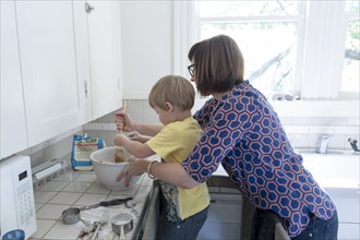 Mother and son baking in kitchen