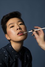 Androgynous woman having makeup applied