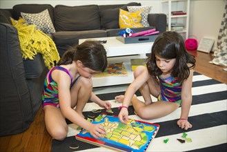 Twin sisters doing puzzle on floor