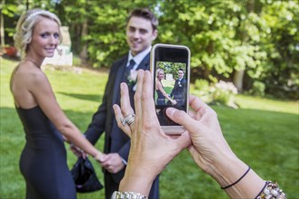 Woman taking cell phone photograph of couple