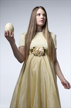 Woman in gown holding egg