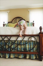 Rear view of baby girl climbing bed