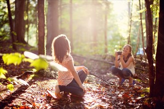 Caucasian girl photographing sister in forest