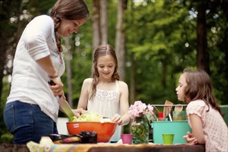 Caucasian mother and daughters cooking outdoors