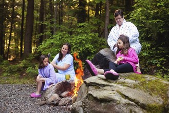 Three generations of Caucasian women sitting around campfire