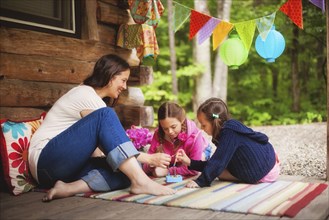 Caucasian mother and daughters playing with toy on cabin porch