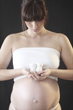 Pregnant Caucasian woman holding baby booties