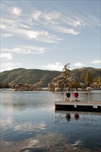 Couple sitting on wooden deck in remote lake