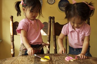Chinese twin girls making cookies at table