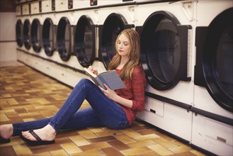 Woman reading book at laundromat