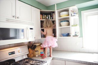 Semi-nude girl looking in cupboard on kitchen counter
