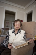 Older Asian woman looking at photo album