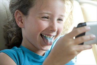 Caucasian girl with blue tongue taking selfie with cell phone